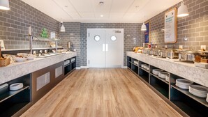 A modern breakfast area with two counters, a wooden floor, and a brick wall. - Holiday Inn Express Wigan by IHG (Wigan)