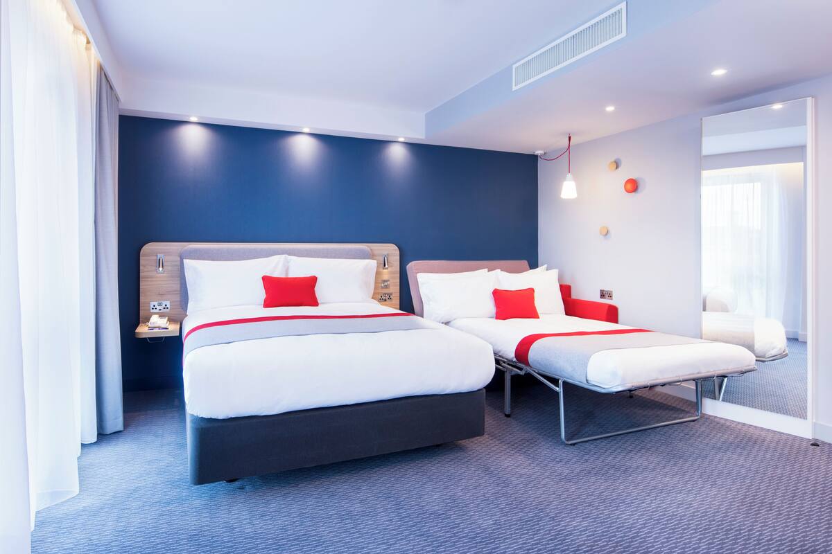A modern hotel room with two beds, a nightstand, and a large window.