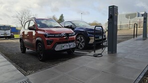 Twee auto's geparkeerd bij een laadstation voor elektrische auto's.