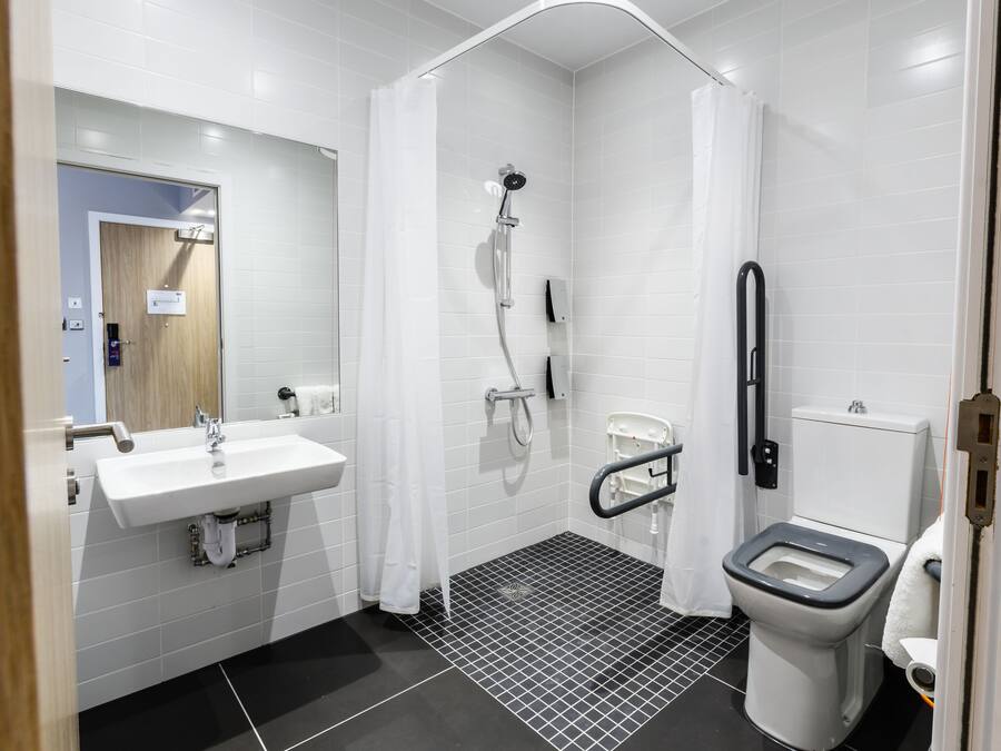 A modern bathroom with a white sink, a shower, and a toilet.