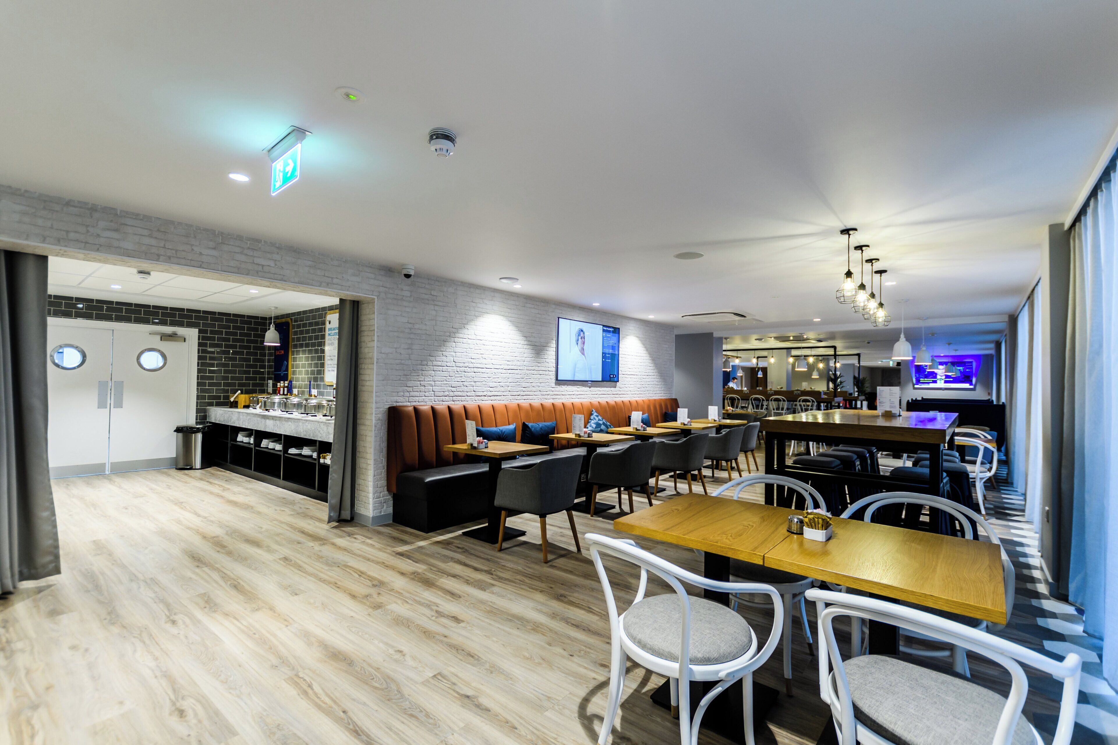 A modern restaurant with a bar area, seating arrangements, and a visible kitchen.