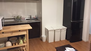 A compact kitchen with a black refrigerator, a sink, and a small countertop. - Shonan Enoshima Seaside Guest House ANNEX (Kamakura)