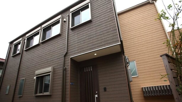A two-story building with a dark brown exterior, a brown door, and a small window on the ground floor. - Shonan Enoshima Seaside Guest House ANNEX (Kamakura)