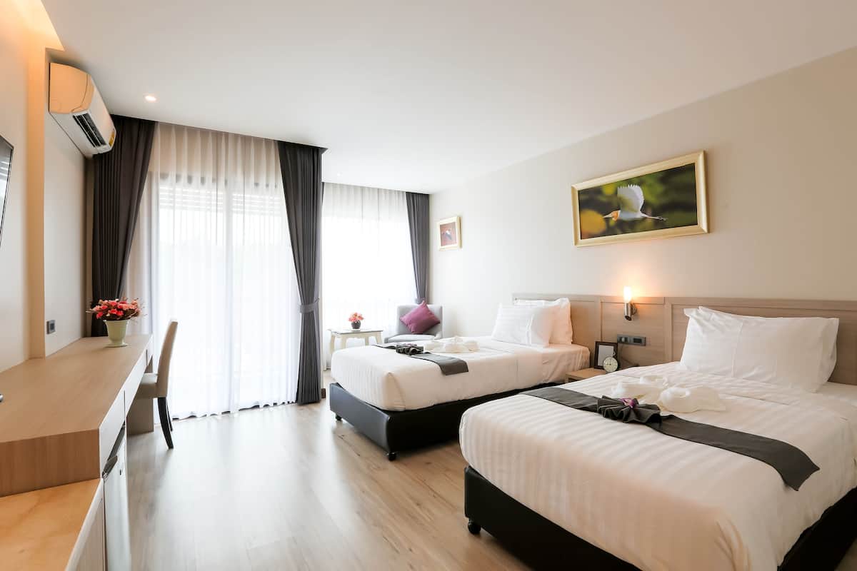 A hotel room with two beds, a desk, and a chair.