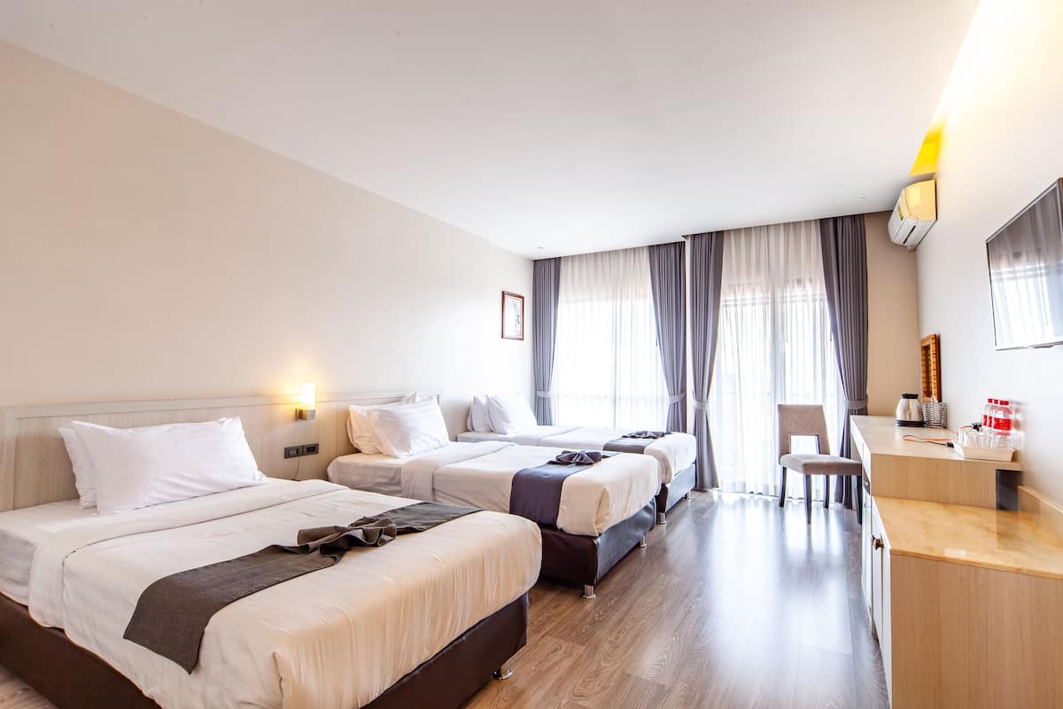 A hotel room with three beds, a desk, and a chair.