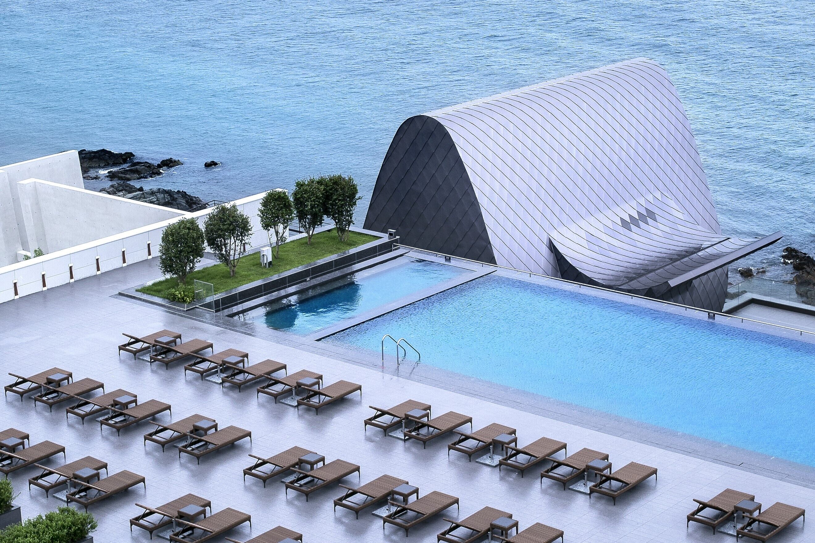 Un espace piscine moderne avec des chaises longues et une grande piscine.
