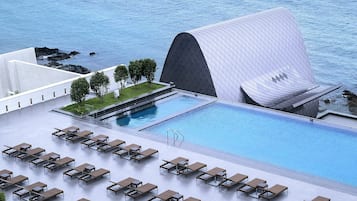 Un espace piscine moderne avec des chaises longues et une grande piscine.