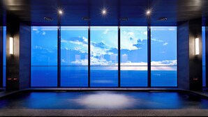 Ein moderner Spa-Bereich mit einem großen Panoramafenster, das Blick auf das Meer und die Stadt bietet.