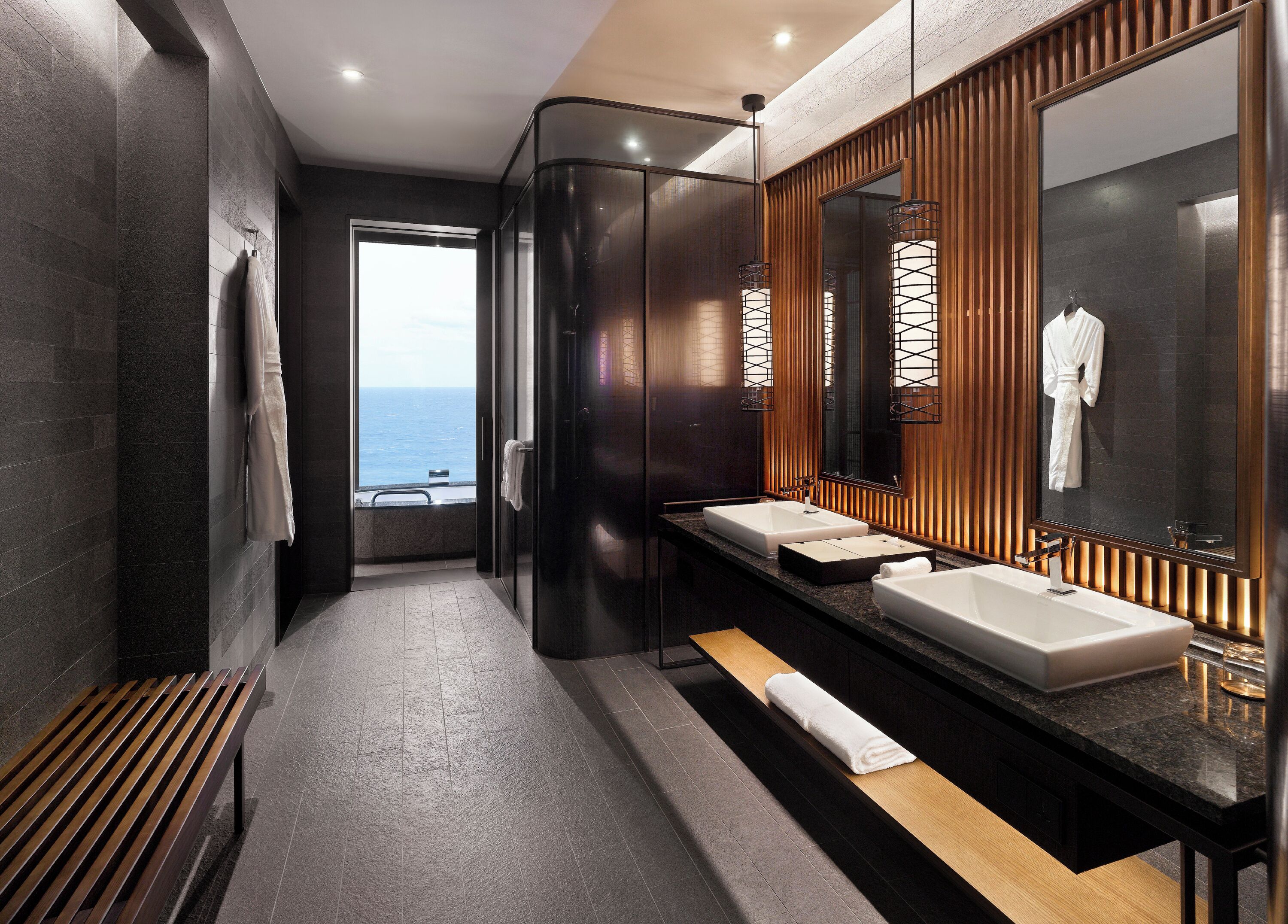 A modern bathroom with two sinks, a large mirror, and a bench.