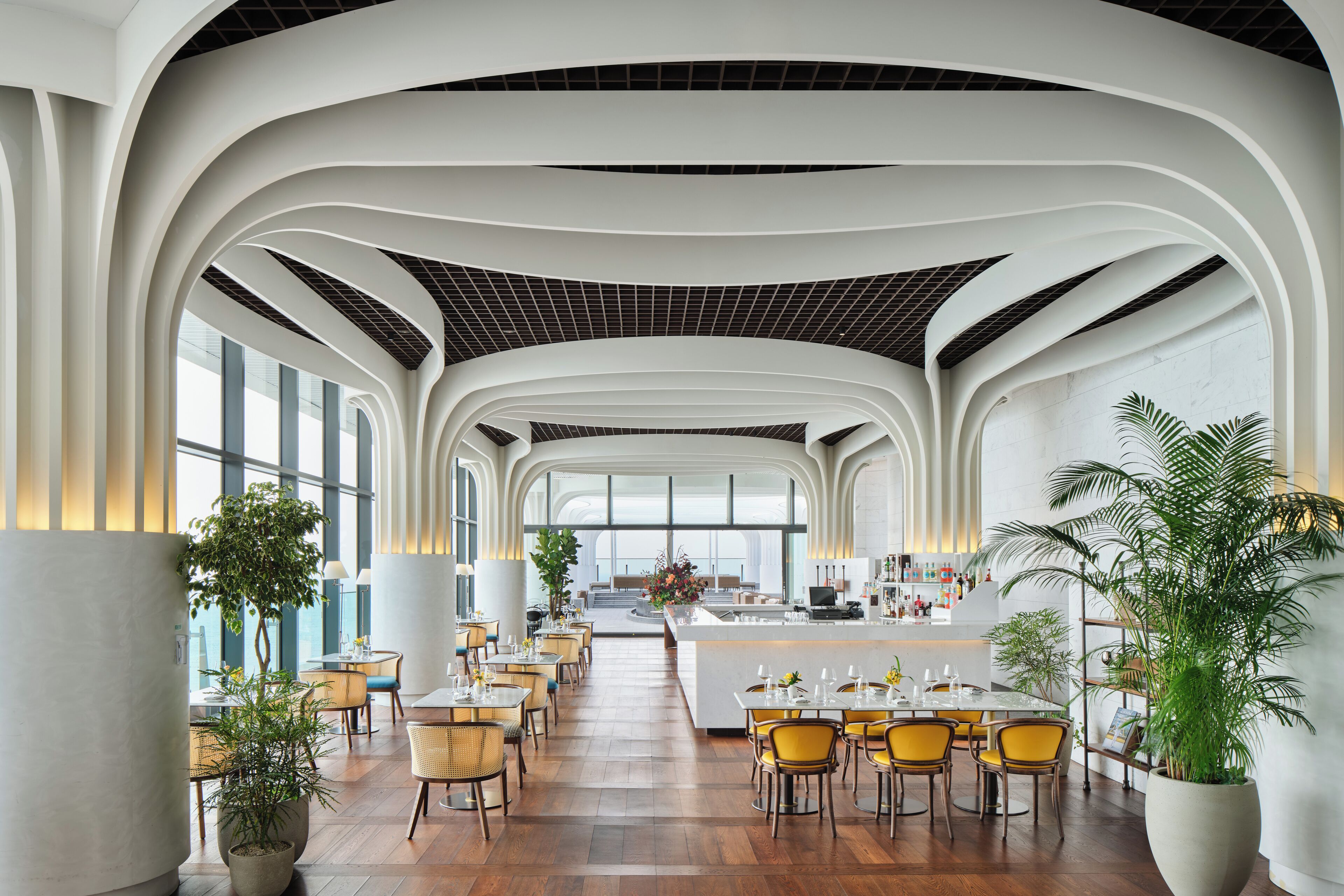 A spacious, modern restaurant with high ceilings, large windows, and a central island.
