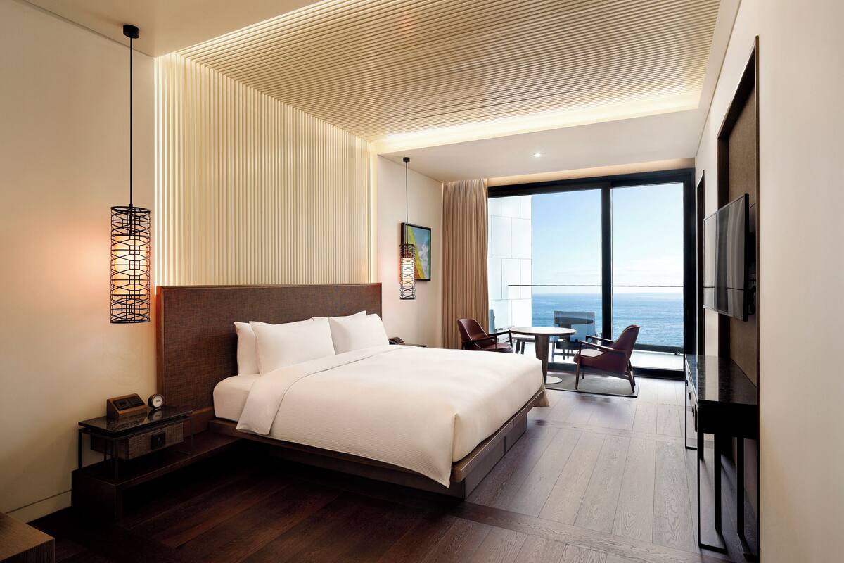 Ein modernes Hotelzimmer mit einem großen Bett, einem Schreibtisch und Blick aufs Meer.