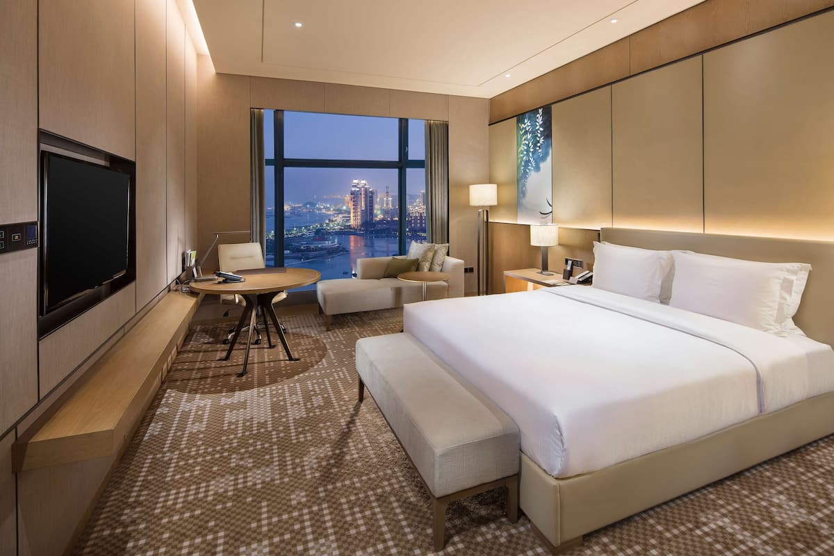 Une chambre d’hôtel moderne équipée d’un grand lit, d’un bureau, d’une chaise, d’un canapé et d’une télévision.