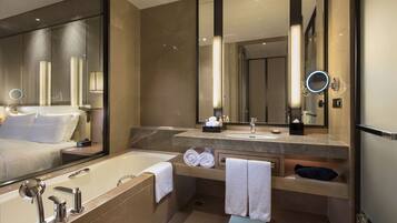 Un baño moderno con un espejo grande, una bañera, un lavabo y un tocador.