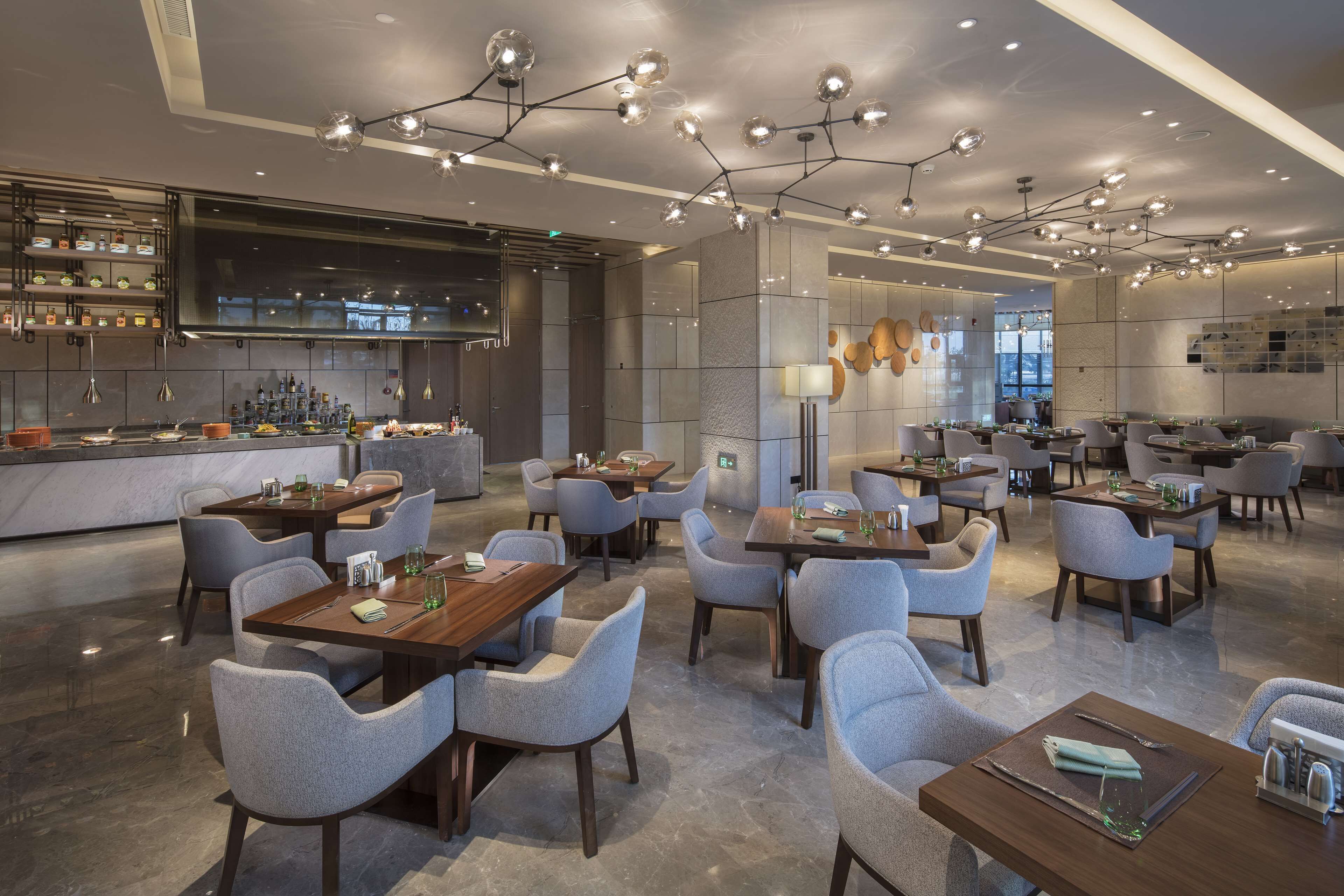 A modern restaurant with multiple dining areas, including a bar and a seating area with tables and chairs.