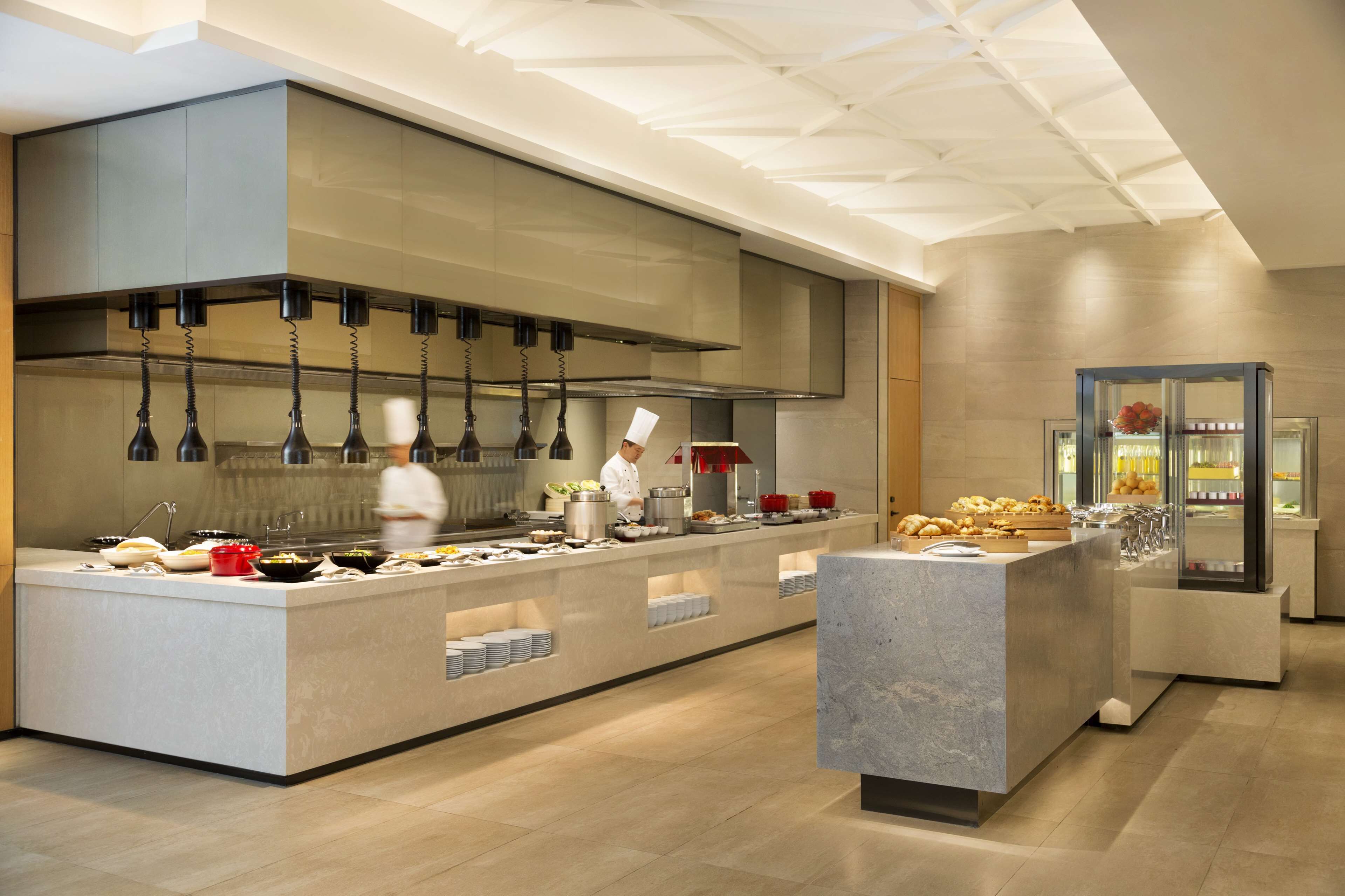 Una cocina moderna con una isla central, electrodomésticos de acero inoxidable y un chef preparando comida.
