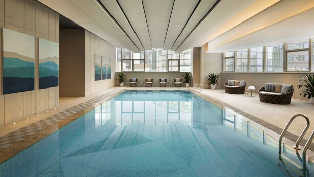 Una piscina interior con paredes de vidrio transparente, asientos acolchados y obras de arte en las paredes.
