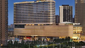 Un hotel moderno con fachada curva, varios pisos y un letrero llamativo en la parte superior.