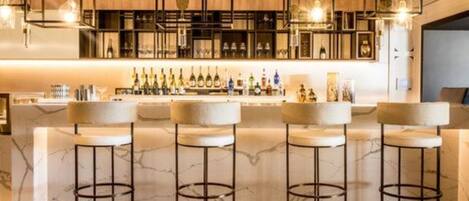 A bar area with a marble countertop, multiple stools, and a variety of bottles.