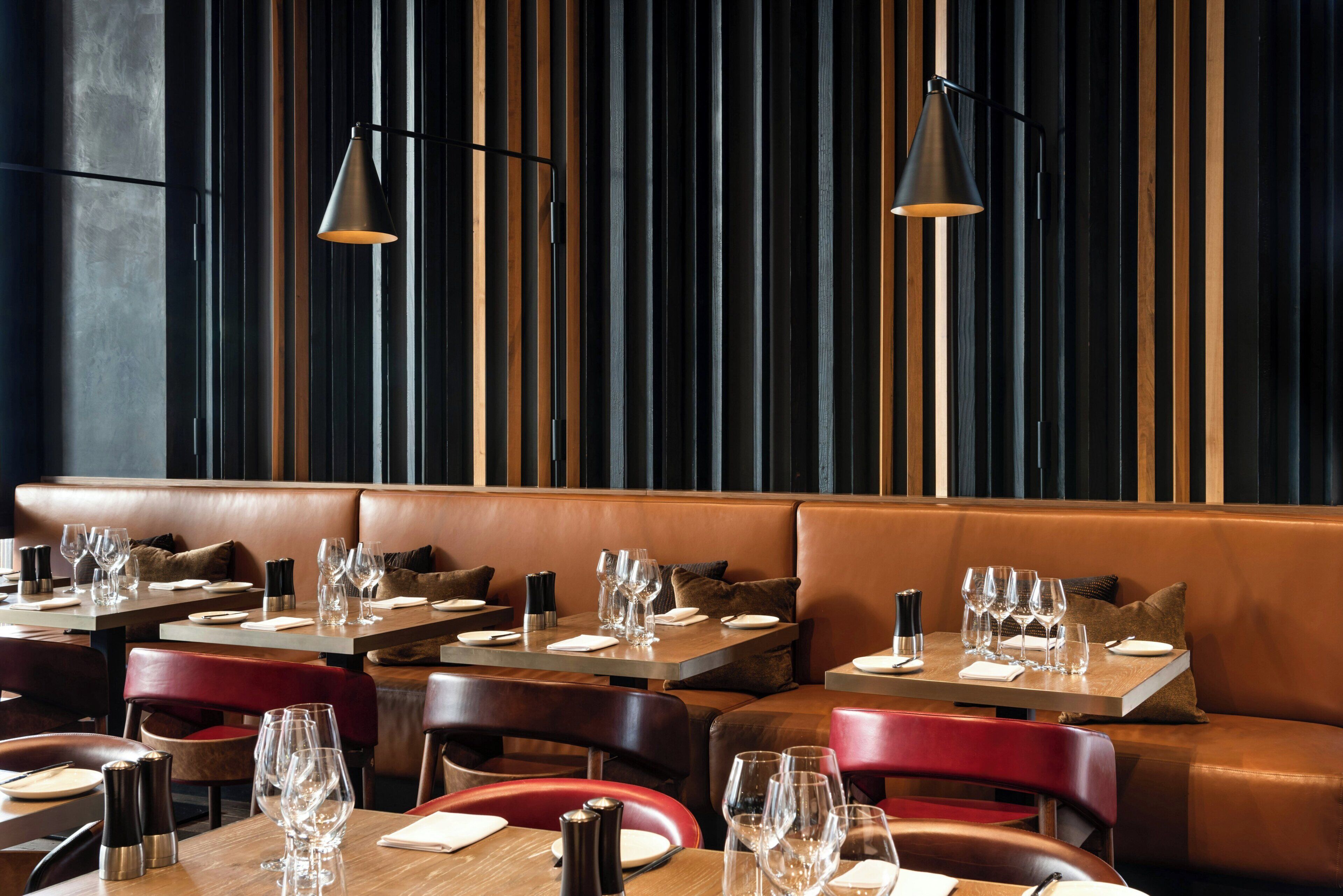 A restaurant interior with booths, tables, and modern lighting fixtures.