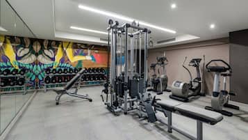 A gym with various exercise equipment, including a bench press, weight machines, and dumbbells.