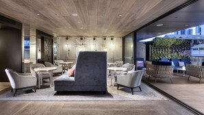 A modern lounge area with a grey sofa, armchairs, and round tables. - InterContinental Perth City Centre by IHG (Perth)