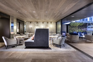A modern lounge area with a grey sofa, armchairs, and round tables. - InterContinental Perth City Centre by IHG (Perth)