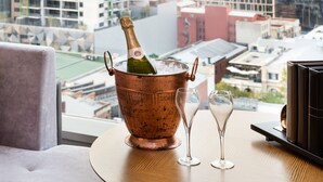 A copper ice bucket with a champagne bottle and two glasses on a round table with a city view. - InterContinental Perth City Centre by IHG (Perth)