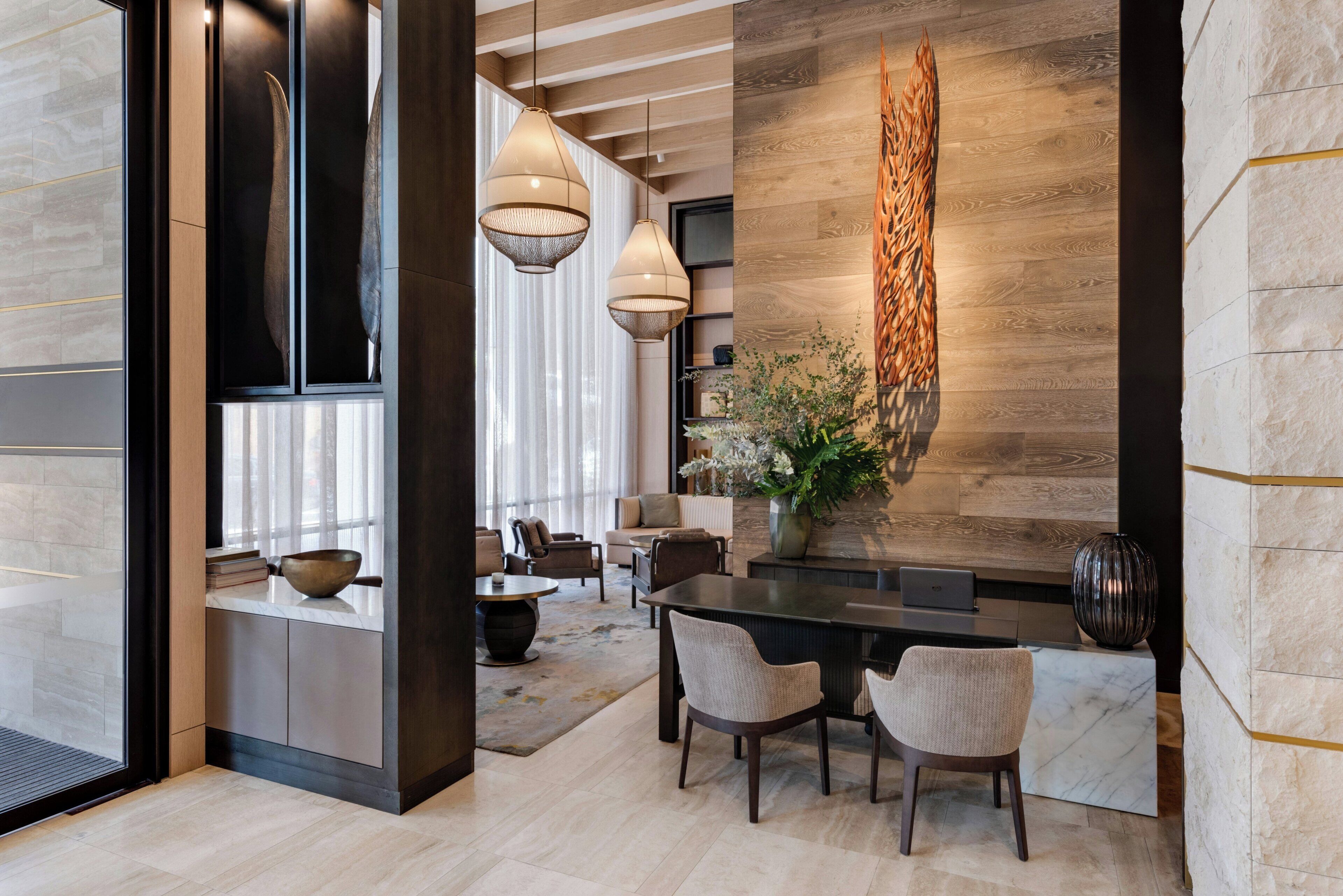 Un comedor moderno con una pared de acento de madera, un jarrón con flores y un portátil sobre la mesa.
