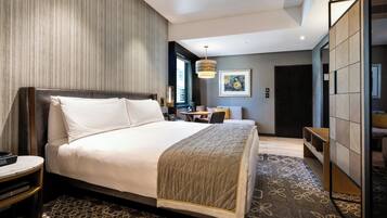 A modern hotel room with a large bed, a desk, and a seating area.