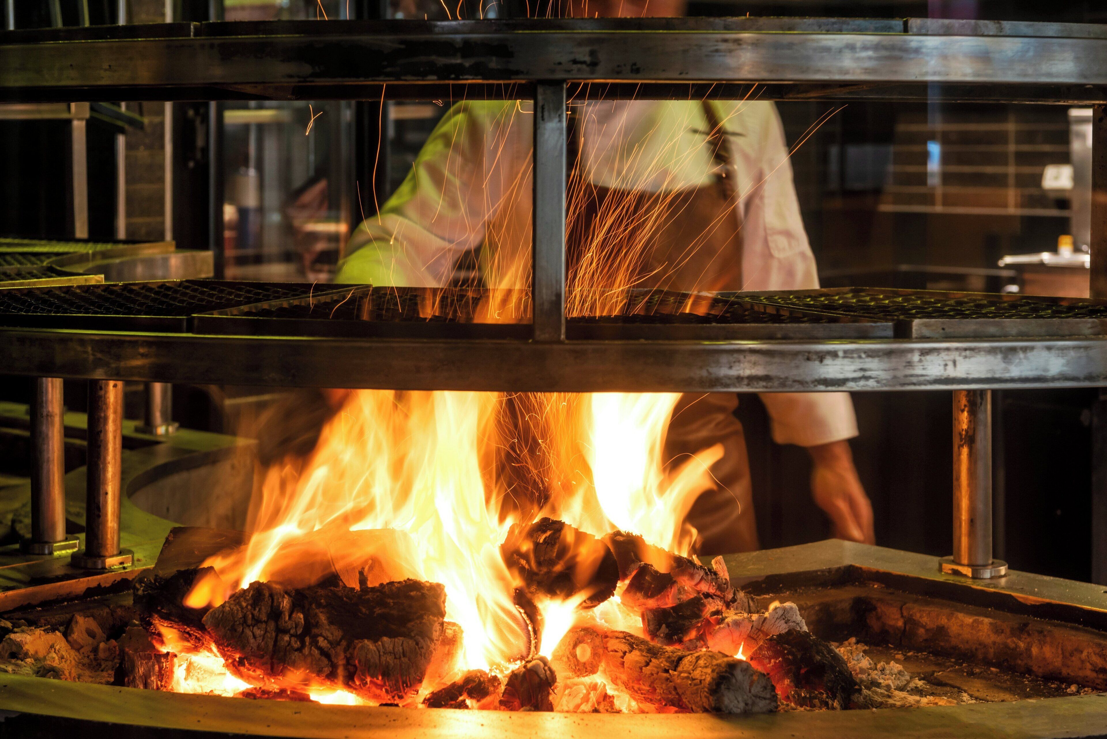 A kitchen with a metal grill and a fire burning underneath.