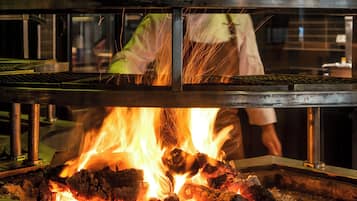 A kitchen with a metal grill and a fire burning underneath.
