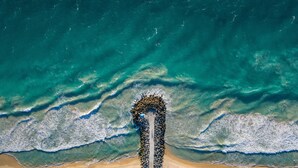 An aerial view of a beach with a long, narrow sandbar extending into the ocean, surrounded by waves. - InterContinental Perth City Centre by IHG (Perth)