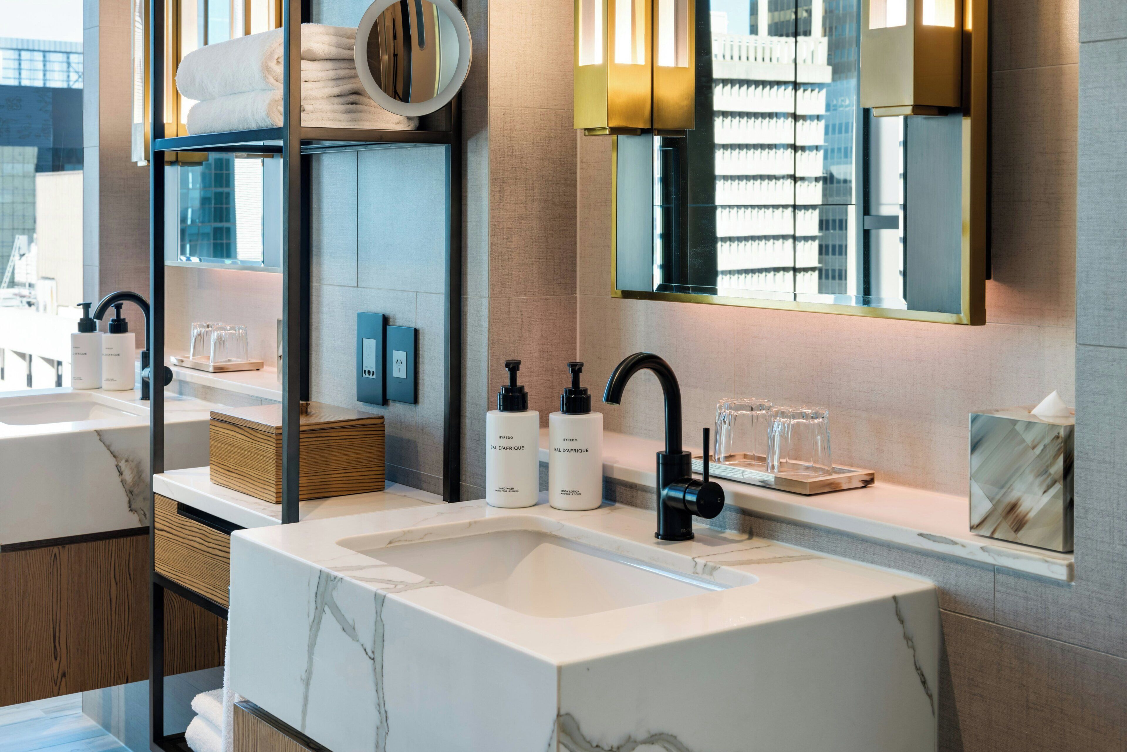 A modern bathroom with a large marble sink, a mirror with integrated lights, and neatly arranged toiletries.