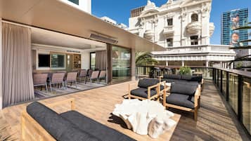 A modern outdoor seating area with sofas and tables, overlooking a historic building with ornate architecture.