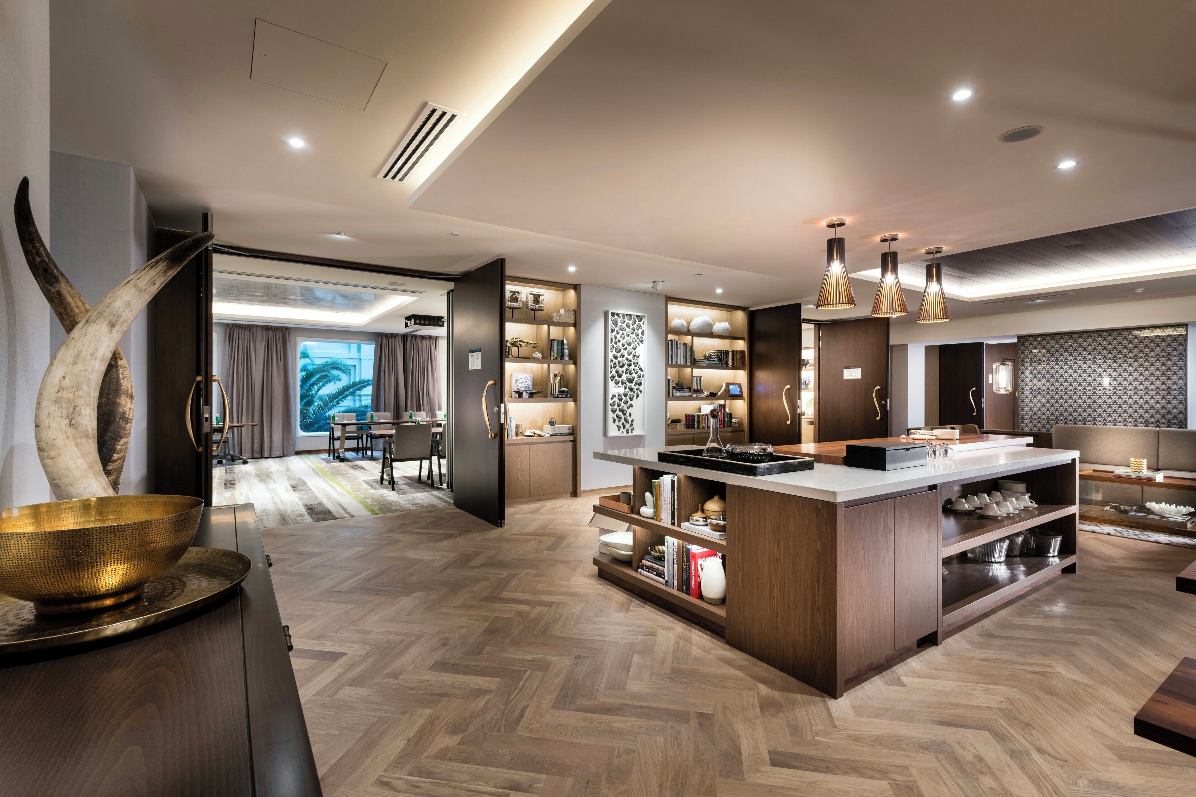 Una cocina moderna con una isla central, suelo de madera e iluminación colgante.