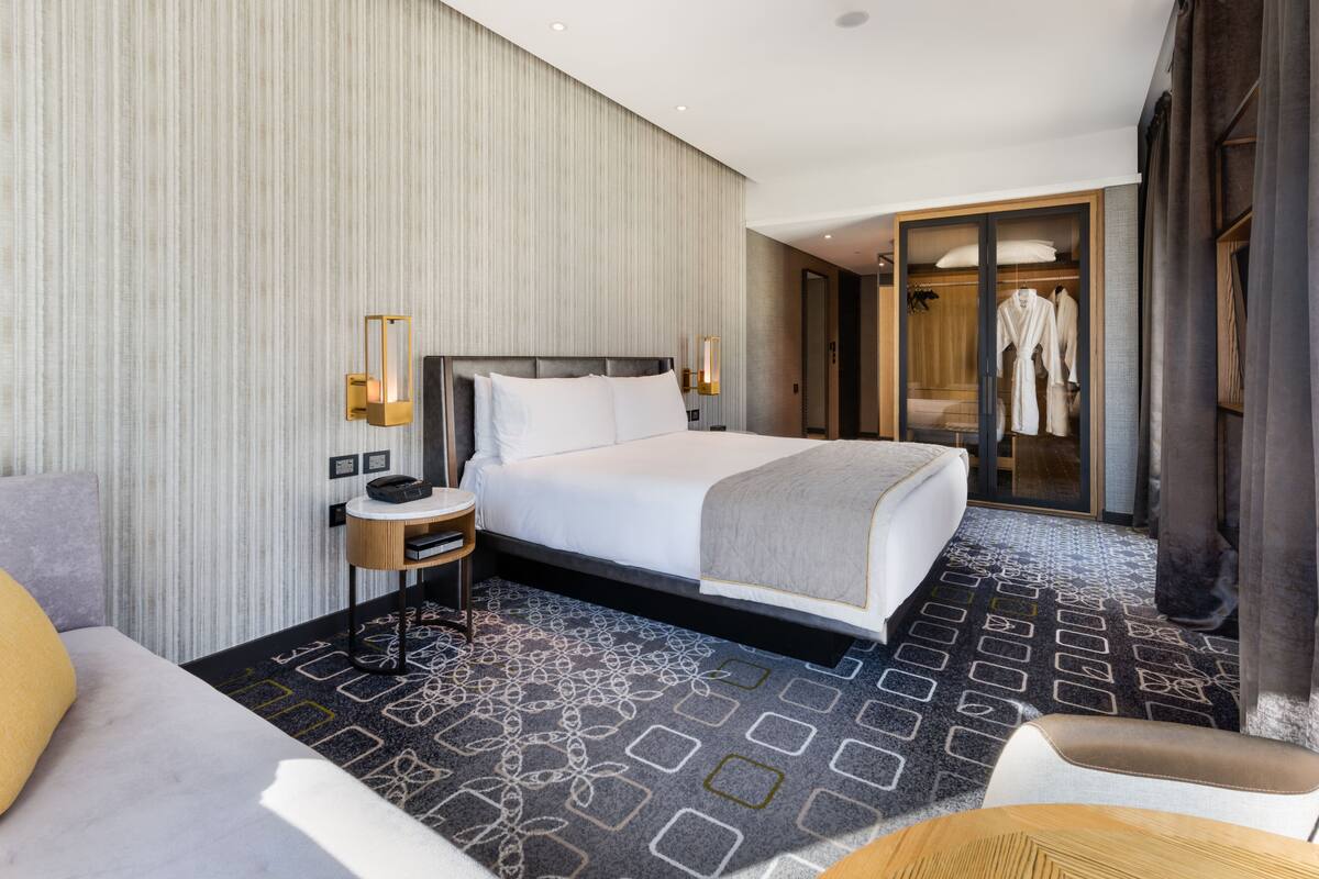 A hotel room with a large bed, bedside tables, a wardrobe, and a patterned carpet.