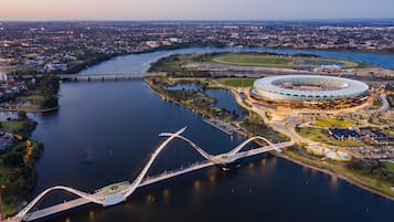 An aerial view of a stadium with a circular design, surrounded by a river and a bridge.