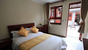 Habitación de hotel con una cama grande, cabecera de madera, mesita de noche y una ventana con cortinas.