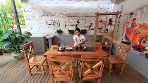 Una terraza de madera con una mesa y sillas, un mural en la pared y plantas en macetas.