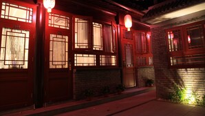 Un edificio tradicional con puertas y ventanas rojas, iluminado por faroles colgantes.