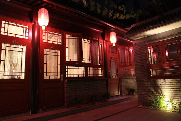 A traditional building with red doors and windows, illuminated by hanging lanterns.