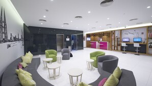 A modern lobby with seating areas, a reception desk, and digital displays. - ibis Styles Manama Diplomatic Area (Manama)