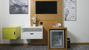 Un mostrador de recepción con un televisor de pantalla plana, un refrigerador pequeño, un teléfono y un armario amarillo.