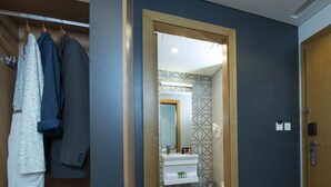Pasillo que conduce a un baño con espejo, lavamanos y pared con diseño.