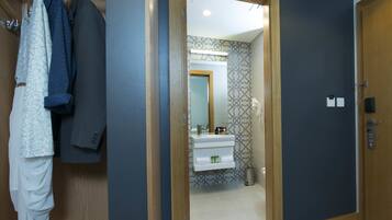 Pasillo que conduce a un baño con espejo, lavamanos y pared con diseño.