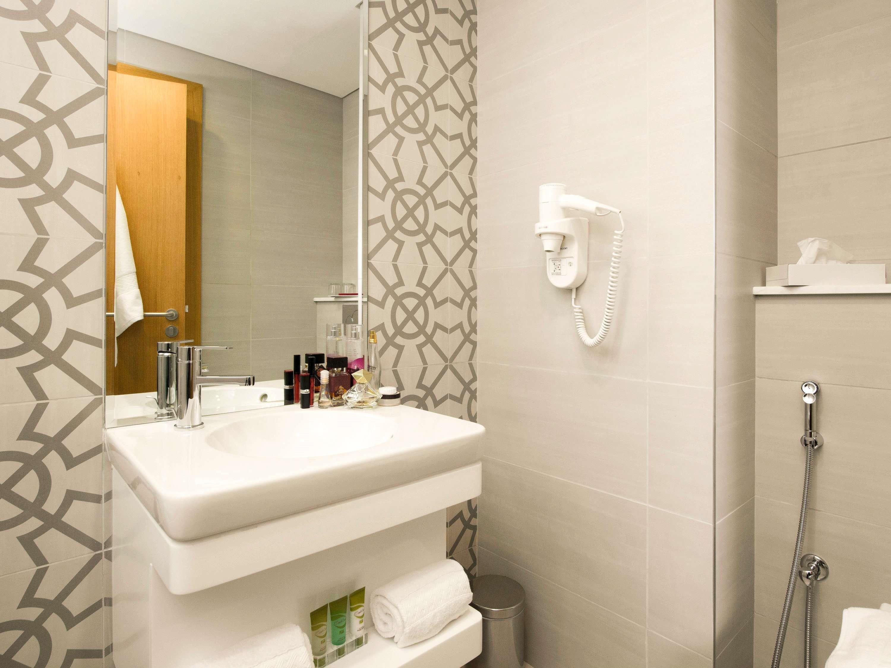 Une salle de bain équipée d’un lavabo, d’un miroir, d’un porte-serviettes et d’une douche.