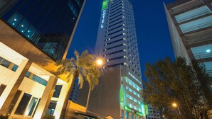 A high-rise hotel with a prominent 'ibis' sign, modern architecture, and a well-lit entrance. - ibis Styles Manama Diplomatic Area (Manama)