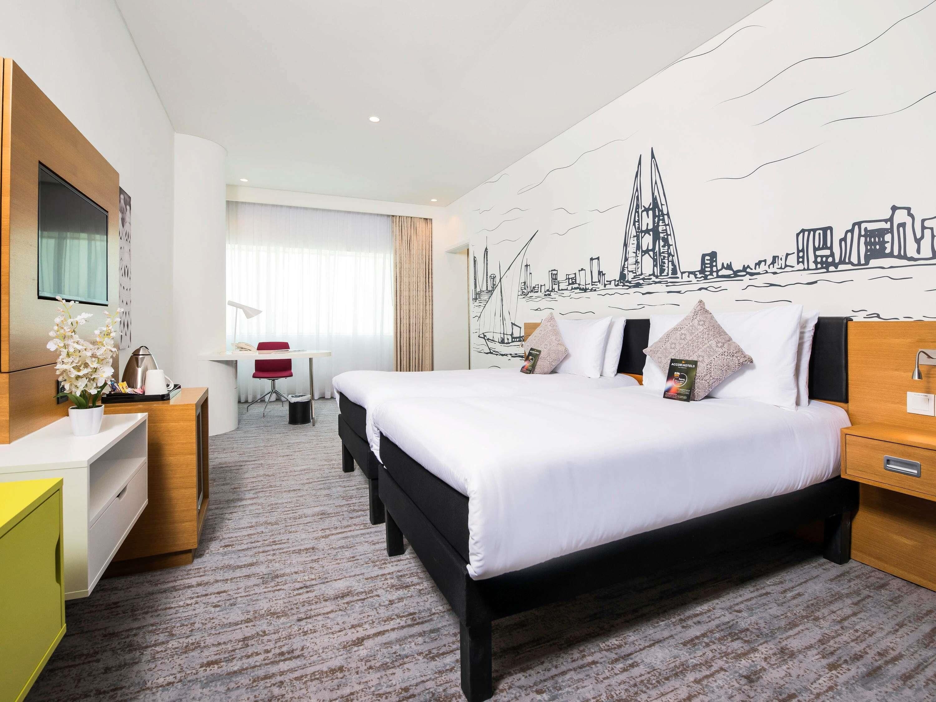 Une chambre d’hôtel avec un lit, un bureau, une chaise et une fresque murale.
