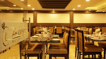 Un restaurante con varias mesas y sillas, un separador de vidrio y un cartel en la pared.