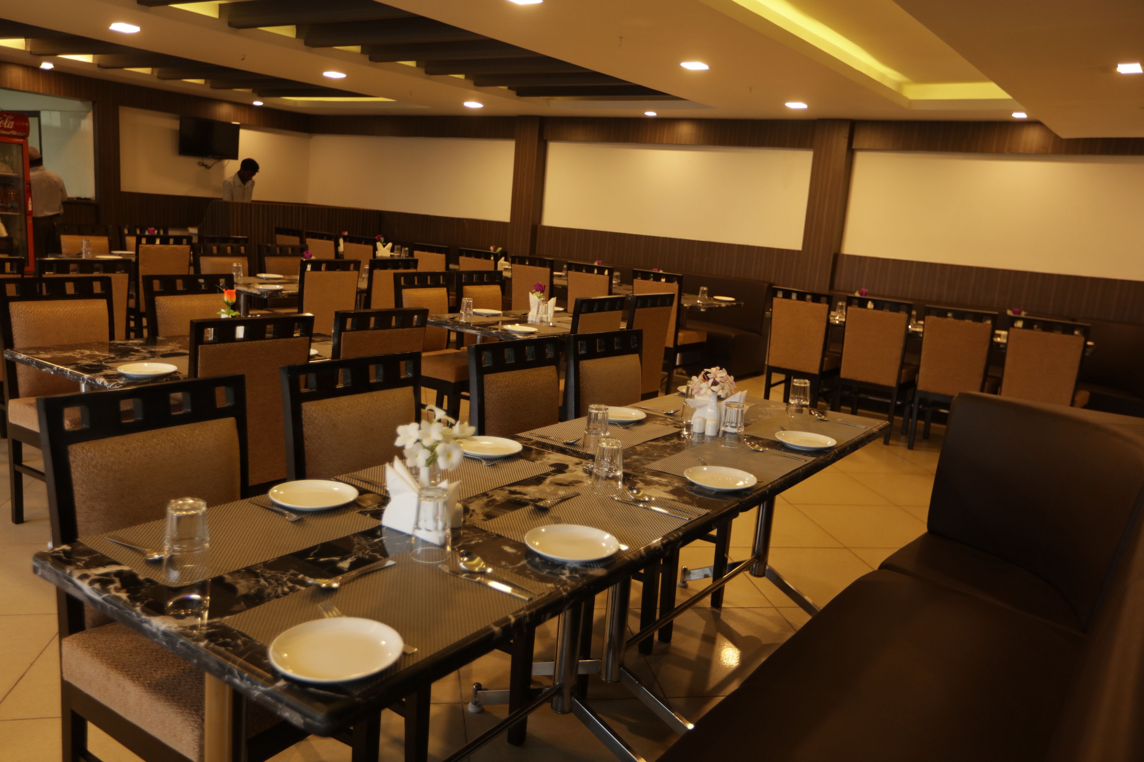 Un salón de conferencias con varias mesas dispuestas para comer, equipado con sillas, platos, cubiertos y vasos.